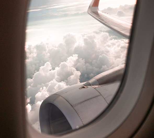 Looking out of an aircraft window towards the wing and engine 